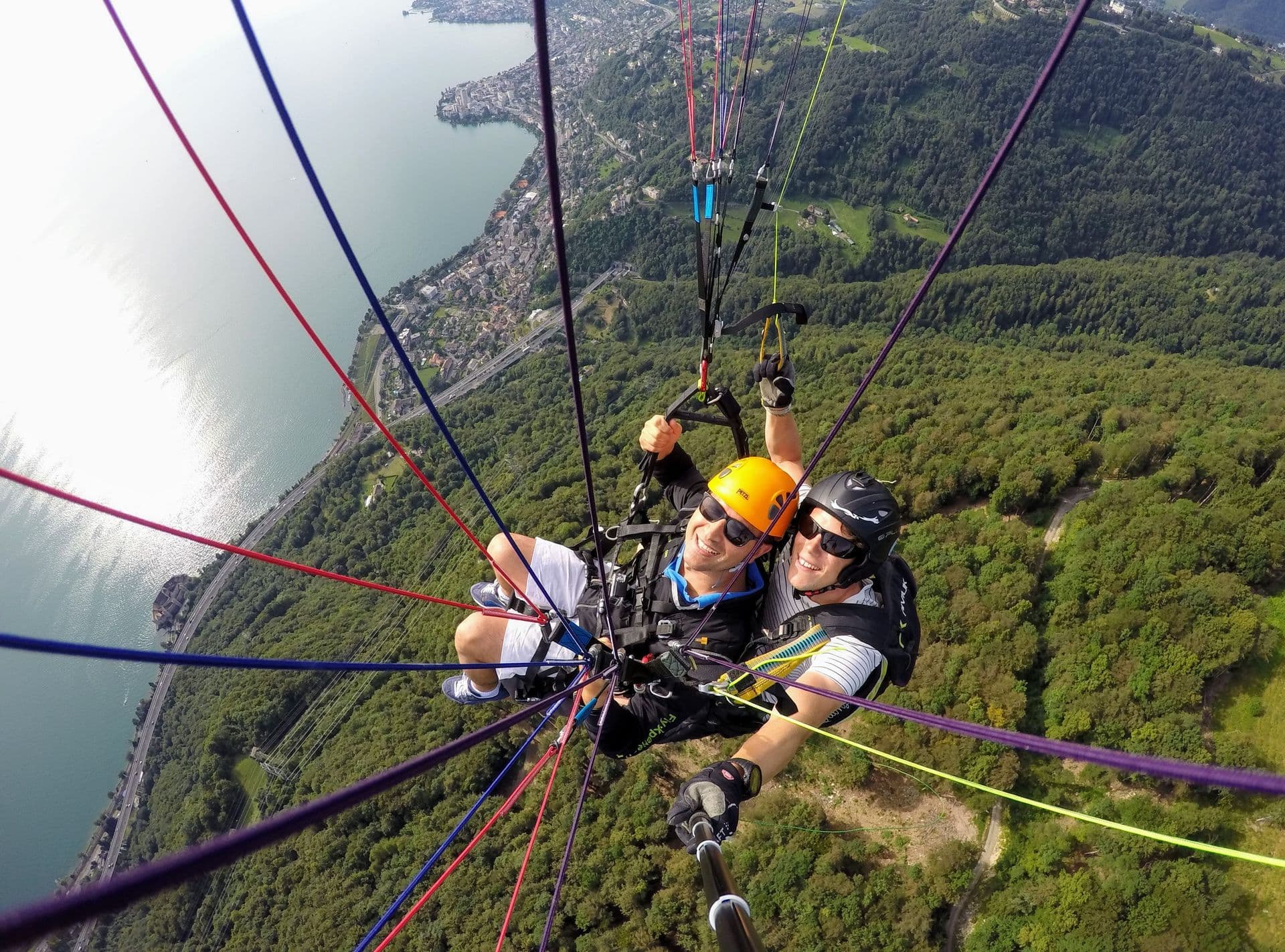 Two people tandem paragliding over a mountain landscape