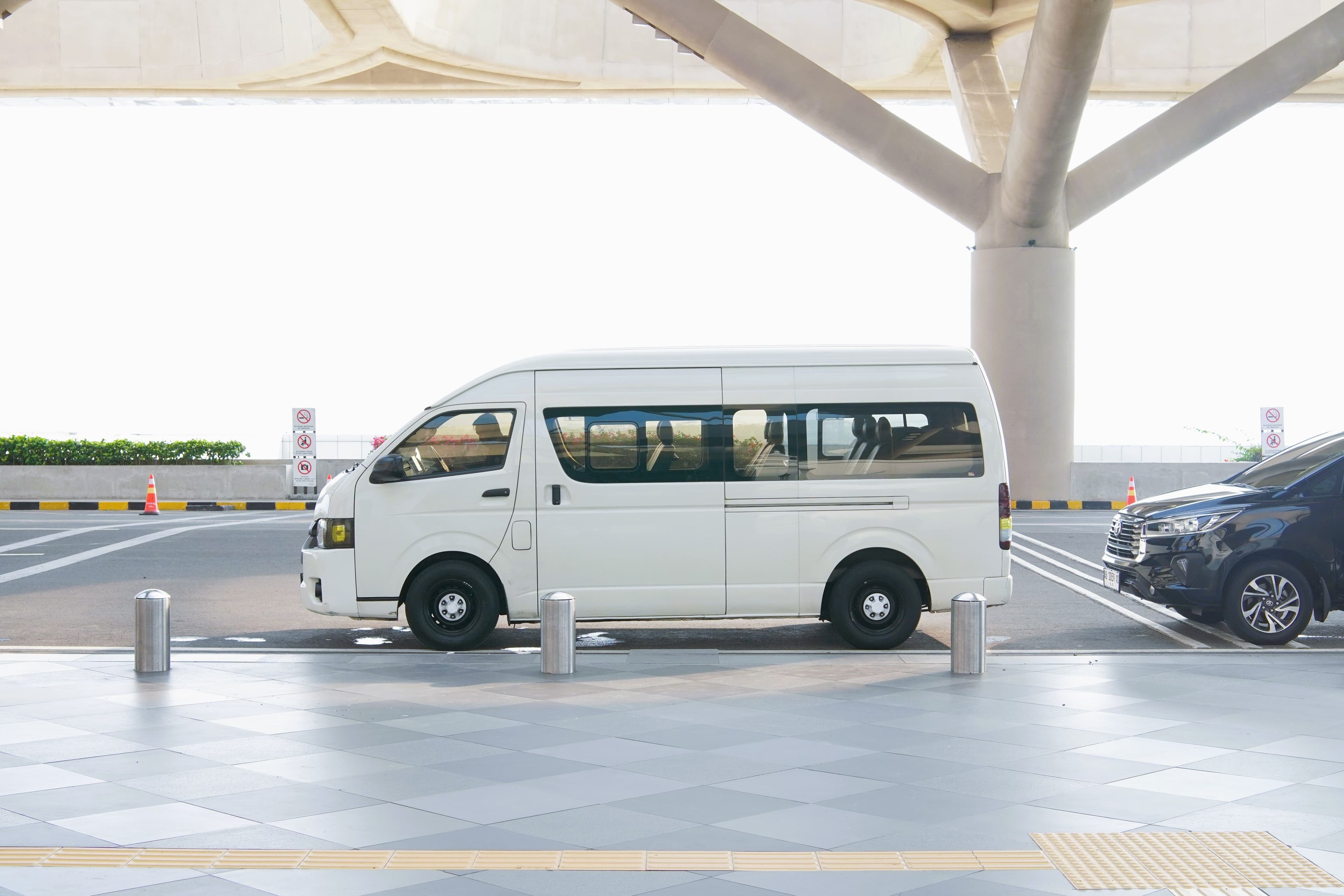 A private transfer minivan parked at an airport terminal drop-off zone